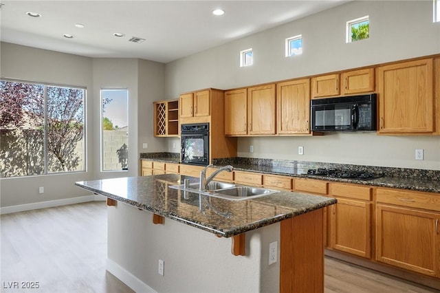 3278 Turning Bridge St, Las Vegas, NV 89135 - kitchen with open shelves, dark stone countertops, a sink, light wood finished floors, and black appliances