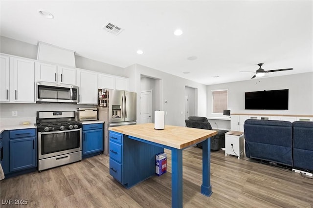 5631 Hill Cliff Ct, North Las Vegas, NV 89031 - kitchen featuring stainless steel appliances, blue cabinets, butcher block countertops, light wood finished floors, and a ceiling fan
