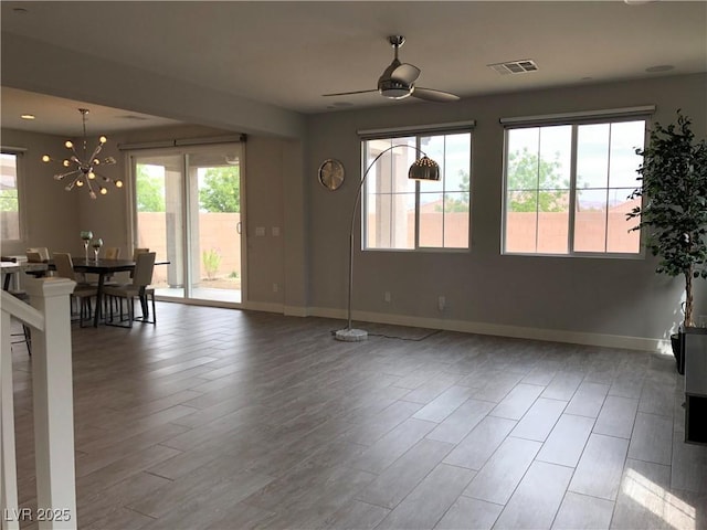 interior space featuring baseboards, plenty of natural light, ceiling fan with notable chandelier, and visible vents