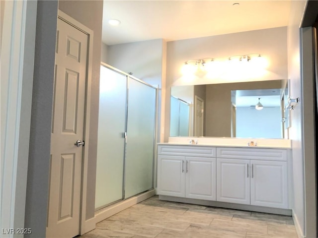 full bath featuring double vanity, a stall shower, wood finished floors, and a sink