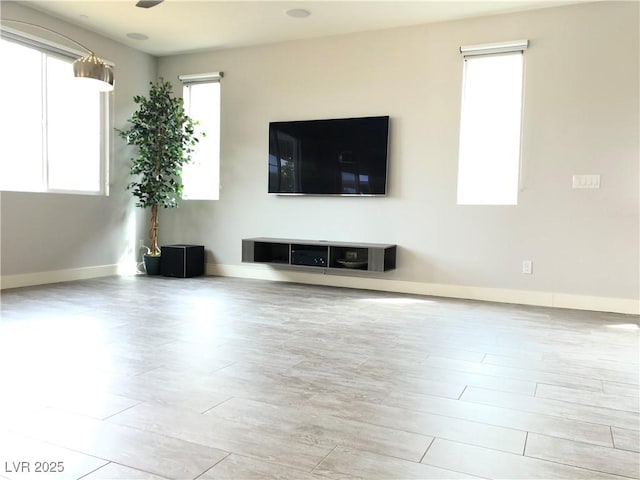unfurnished living room with baseboards and wood finished floors