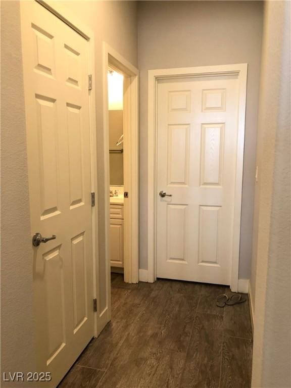 hall featuring dark wood-style flooring and baseboards