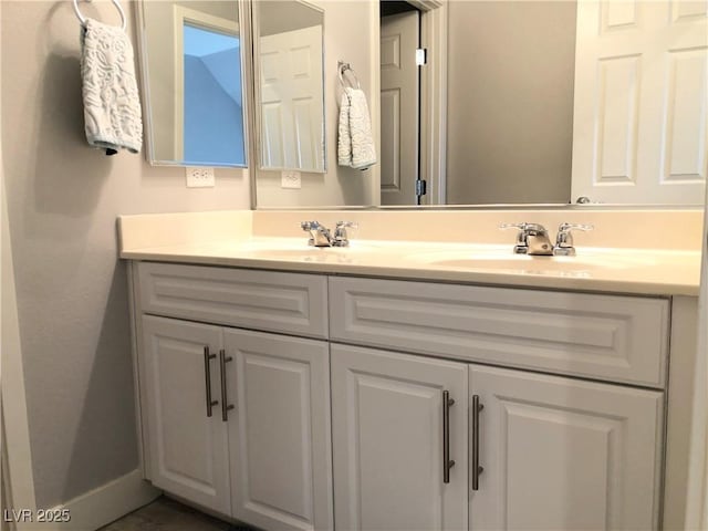 bathroom featuring double vanity, baseboards, and a sink