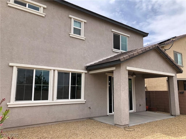 rear view of house featuring a patio, fence, and stucco siding