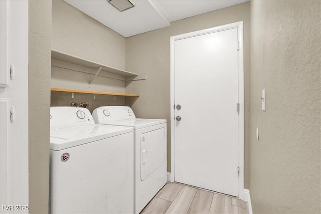 clothes washing area featuring laundry area, light wood finished floors, and washer and clothes dryer