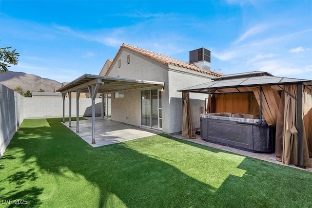 back of house featuring a patio area, a hot tub, a gazebo, a fenced backyard, and stucco siding