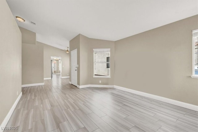 empty room with baseboards, light wood-style flooring, vaulted ceiling, and visible vents
