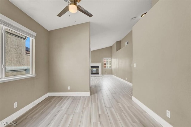 spare room with baseboards, a ceiling fan, light wood-style flooring, and a premium fireplace