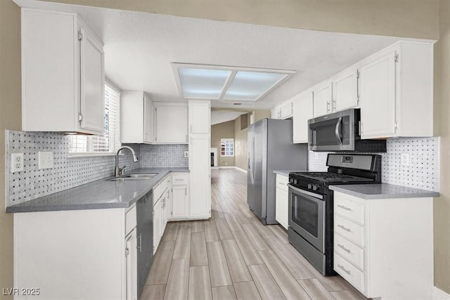 kitchen with a sink, white cabinetry, a wealth of natural light, and stainless steel appliances