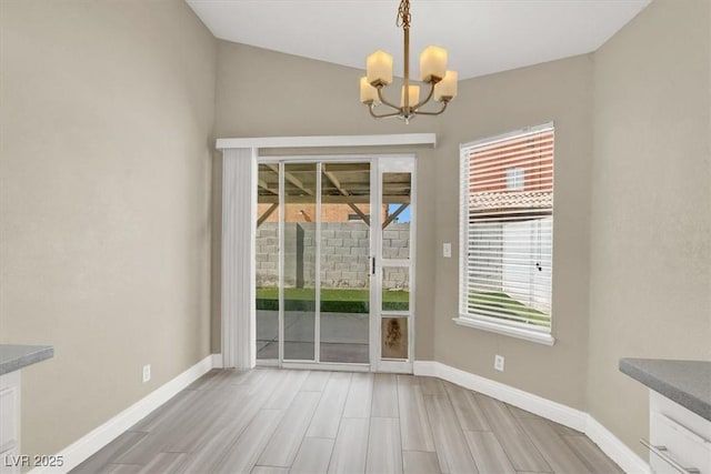 unfurnished dining area featuring baseboards, wood finish floors, and a notable chandelier