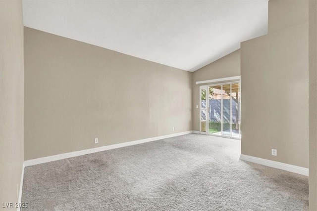carpeted spare room featuring baseboards and vaulted ceiling