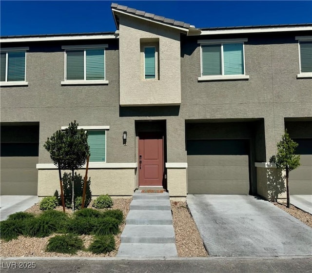 multi unit property featuring a garage, stucco siding, and driveway