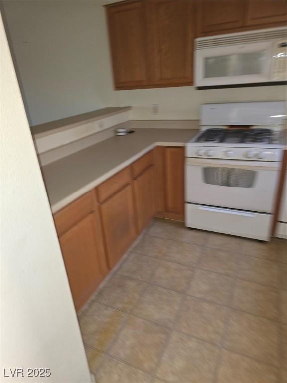 833 Aspen Peak Loop Unit 1524, Henderson, NV 89011 - kitchen featuring brown cabinetry, light countertops, light tile patterned flooring, and white appliances