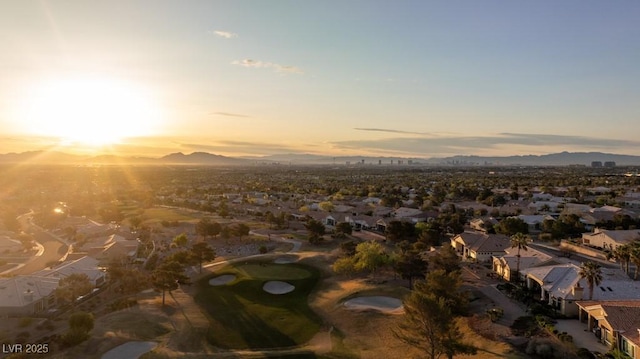 aerial view at dusk with view of golf course, a mountain view, and a residential view