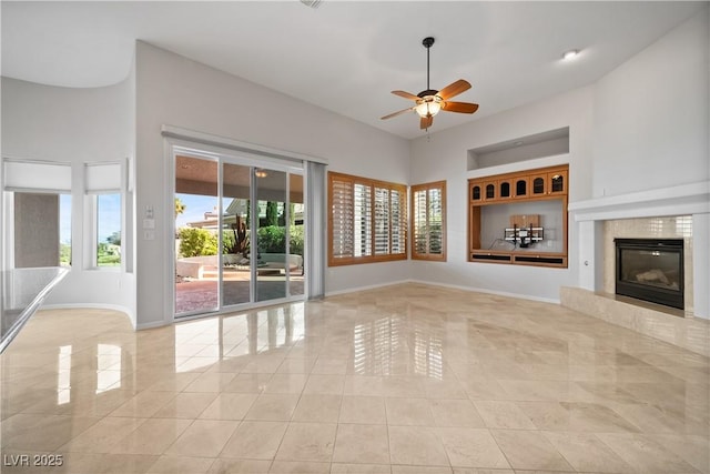 2742 Darby Falls Dr, Las Vegas, NV 89134 - unfurnished living room with baseboards, ceiling fan, tile patterned floors, a fireplace, and a towering ceiling