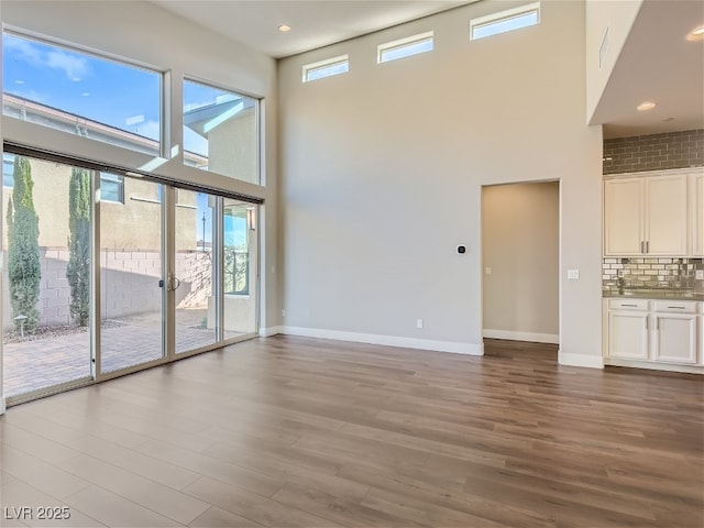 3008 Barrett Springs Ave, Henderson, NV 89044 - unfurnished living room with baseboards, a high ceiling, and wood finished floors