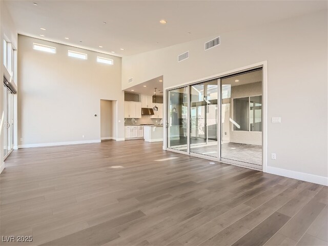 3008 Barrett Springs Ave, Henderson, NV 89044 - unfurnished living room with visible vents, a towering ceiling, a wealth of natural light, and light wood-type flooring