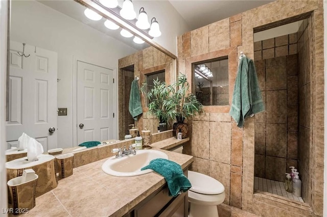 full bath featuring toilet, a tile shower, and vanity