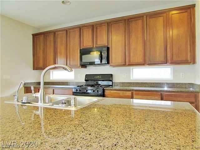 1004 Windy Ferrell Ave, North Las Vegas, NV 89081 - kitchen featuring black appliances, brown cabinetry, a sink, and light stone counters