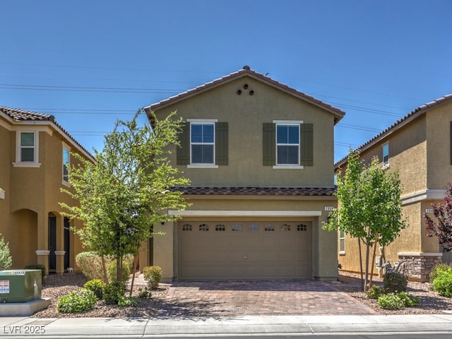 traditional-style home featuring a tiled roof, stucco siding, an attached garage, and decorative driveway