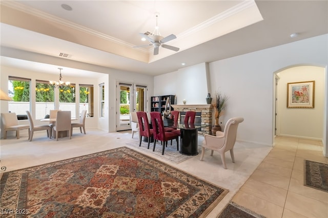 dining area with a raised ceiling, arched walkways, ceiling fan with notable chandelier, baseboards, and visible vents