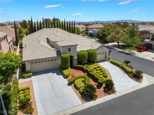 view of front of property featuring driveway, a tile roof, a garage, a mountain view, and stucco siding