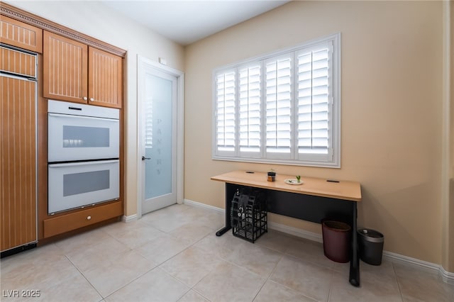 kitchen featuring light tile patterned floors, baseboards, double oven, and built in fridge