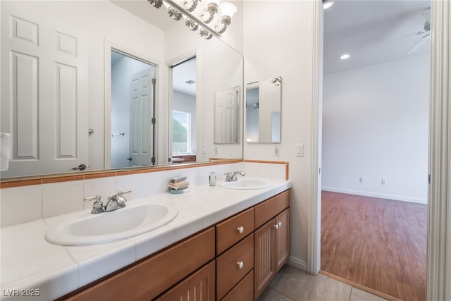 full bath with double vanity, baseboards, and a sink