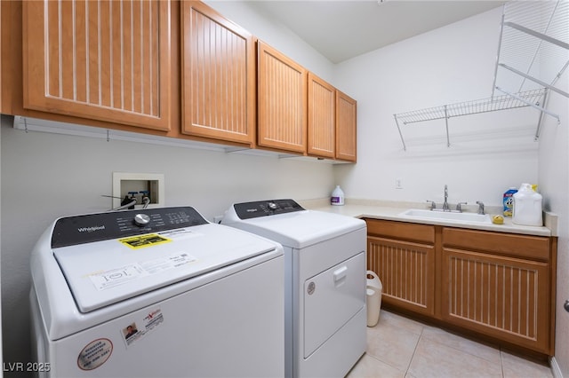 laundry room with a sink, cabinet space, washing machine and dryer, and light tile patterned flooring