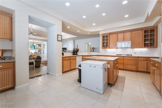 kitchen featuring a kitchen island, tasteful backsplash, light tile patterned floors, light countertops, and white appliances