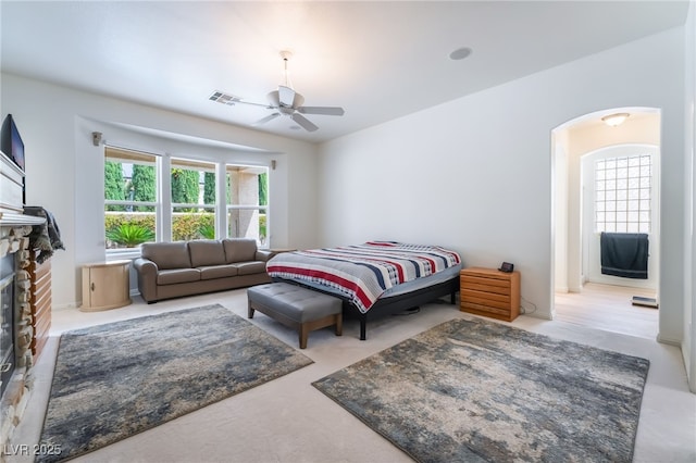 bedroom with arched walkways, visible vents, multiple windows, and a glass covered fireplace