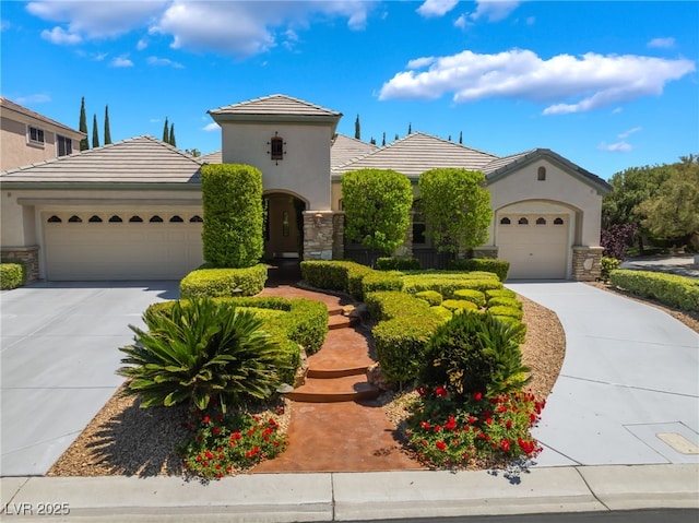 mediterranean / spanish-style house with an attached garage, driveway, a tiled roof, and stone siding