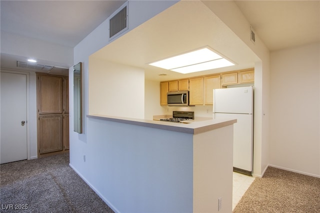 8070 W Russell Rd Unit 1028, Las Vegas, NV 89113 - kitchen with freestanding refrigerator, stainless steel microwave, stove, a peninsula, and light carpet