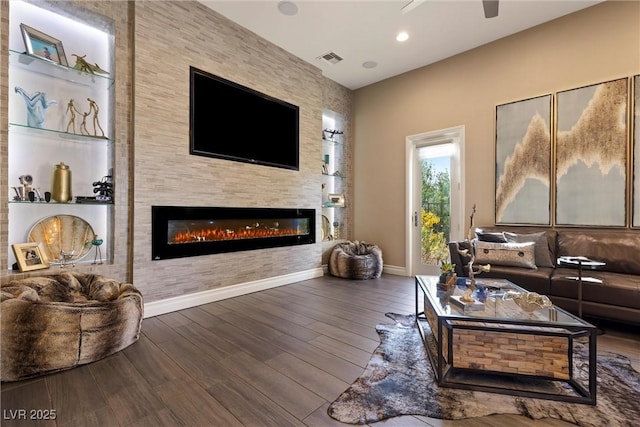 17 Grand Corniche Dr, Henderson, NV 89011 - living room with visible vents, a glass covered fireplace, wood finished floors, baseboards, and ceiling fan
