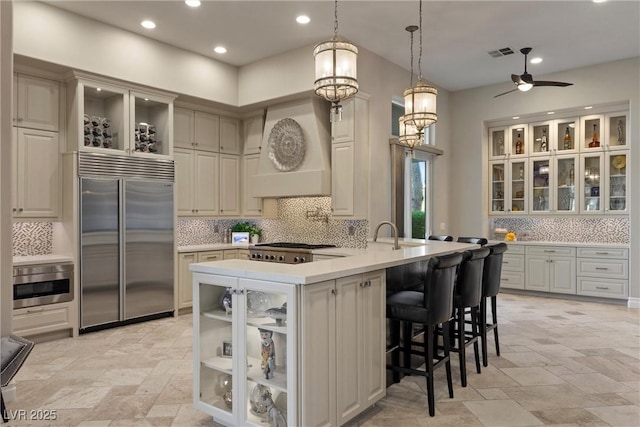 17 Grand Corniche Dr, Henderson, NV 89011 - kitchen featuring backsplash, visible vents, premium range hood, stainless steel appliances, and stone tile floors