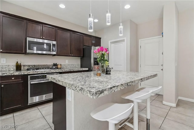 kitchen featuring stainless steel appliances, light tile patterned flooring, a kitchen bar, a kitchen island, and recessed lighting