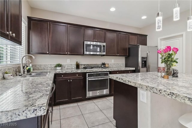 kitchen featuring stainless steel appliances, a sink, light tile patterned floors, dark brown cabinets, and hanging light fixtures