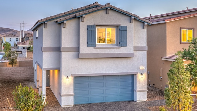 view of front of home featuring an attached garage, decorative driveway, and stucco siding