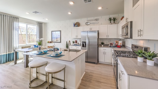 kitchen with a sink, appliances with stainless steel finishes, white cabinets, and visible vents