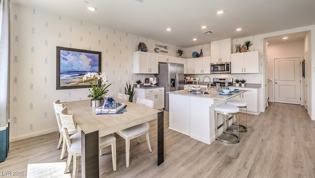 kitchen with appliances with stainless steel finishes, baseboards, white cabinets, light wood finished floors, and recessed lighting