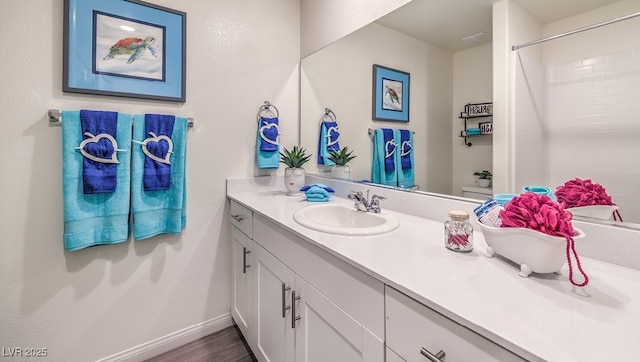 bathroom with vanity, toilet, baseboards, wood finished floors, and a shower