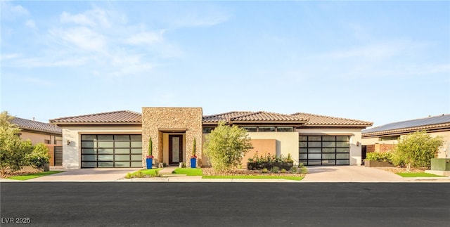 view of front facade with a tiled roof, an attached garage, driveway, and stucco siding