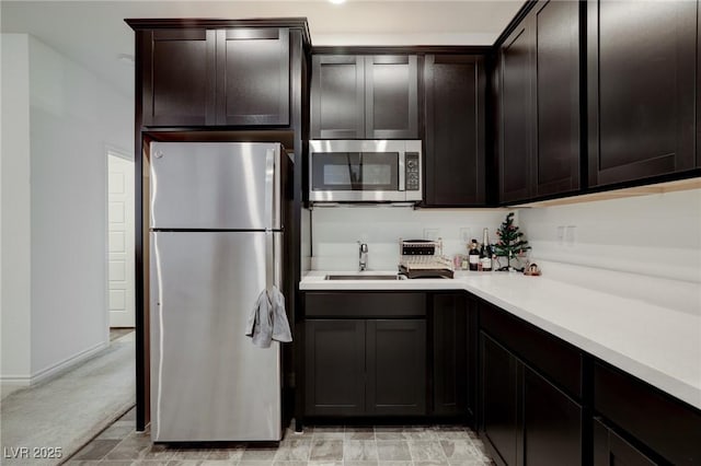 242 Polaris Ridge Ave, Henderson, NV 89011 - kitchen featuring dark brown cabinetry, appliances with stainless steel finishes, a sink, light countertops, and baseboards
