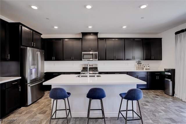 242 Polaris Ridge Ave, Henderson, NV 89011 - kitchen with a center island with sink, appliances with stainless steel finishes, light countertops, and a kitchen bar