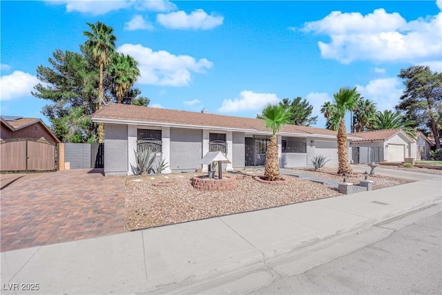 ranch-style house featuring driveway, stucco siding, a gate, and fence