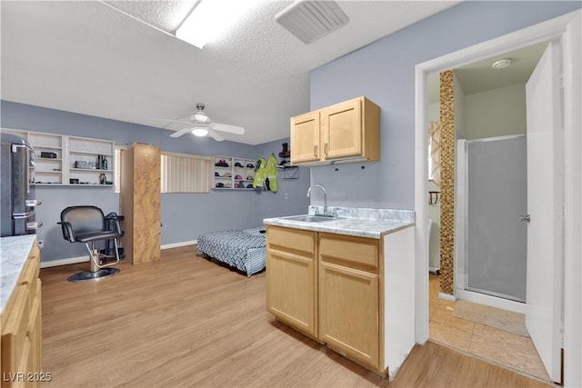 kitchen featuring a sink, visible vents, ceiling fan, light brown cabinetry, and light countertops