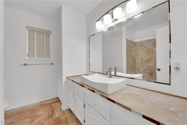 bathroom with vanity, baseboards, toilet, and a tile shower