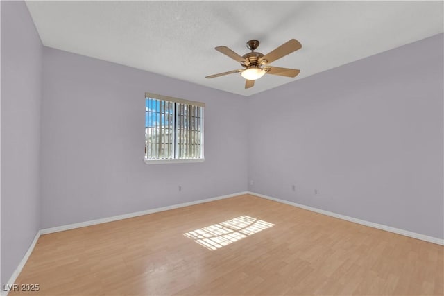 spare room featuring ceiling fan, baseboards, and light wood finished floors