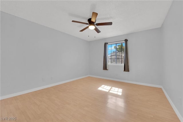 spare room featuring baseboards, wood finished floors, and a ceiling fan