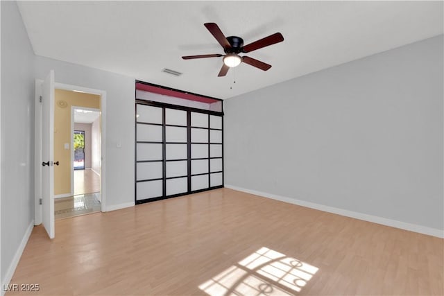 spare room with a ceiling fan, baseboards, visible vents, and wood finished floors